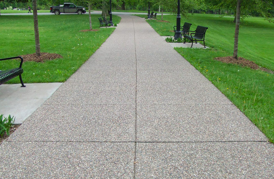Concrete walkway lined with benches and saplings stretching through a Lehigh Valley city park.