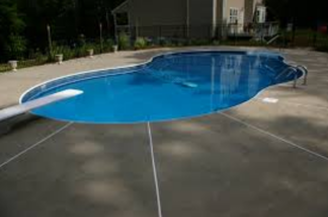 A clean, newly constructed swimming pool with a diving board over clear blue water, new tile, and white concrete sealant along the seams in a backyard of a home in Lehigh Valley.
